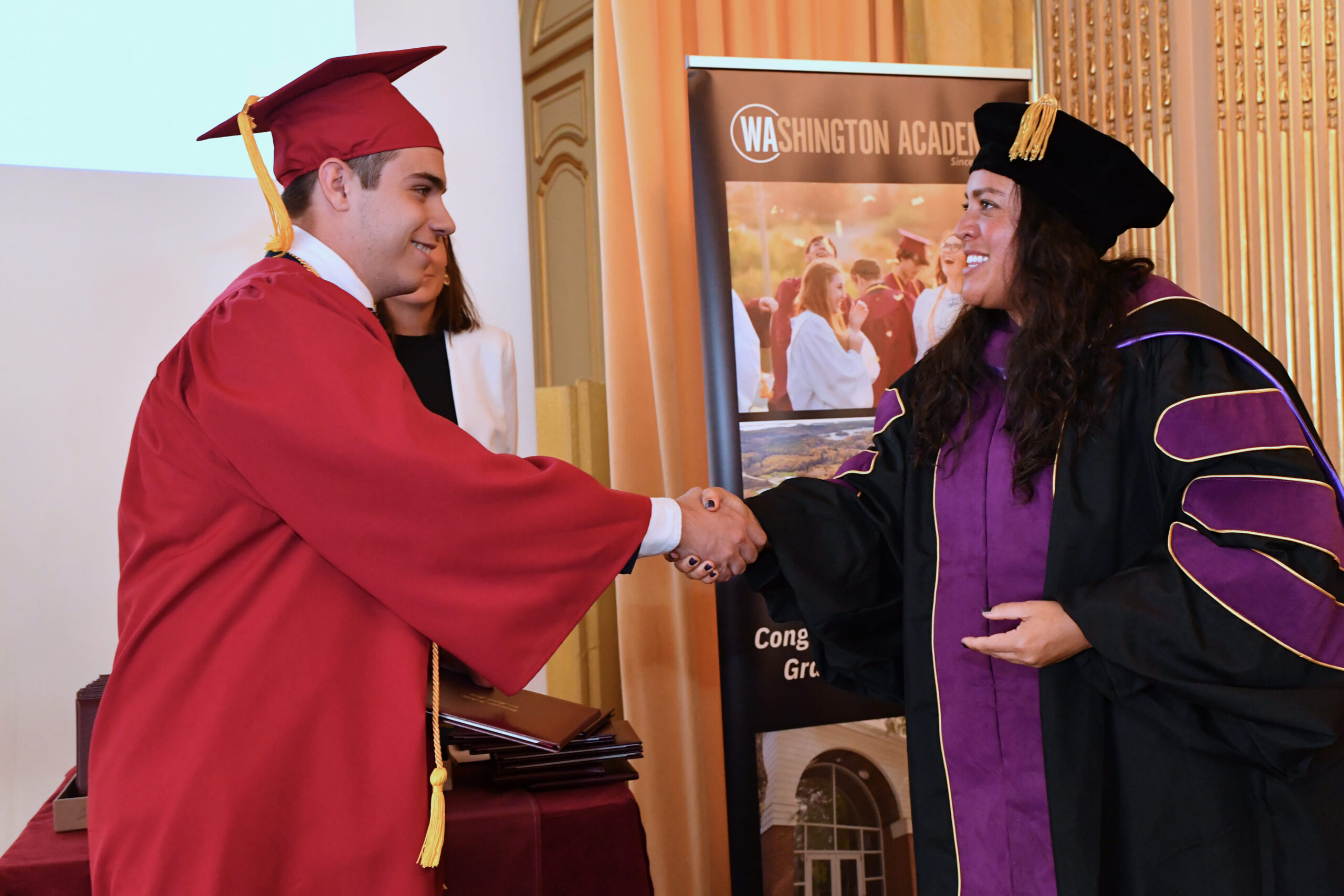 El alumno da la mano a la directoria del colegio en la ceremonia de la graduacion del programa de Diploma Dual.