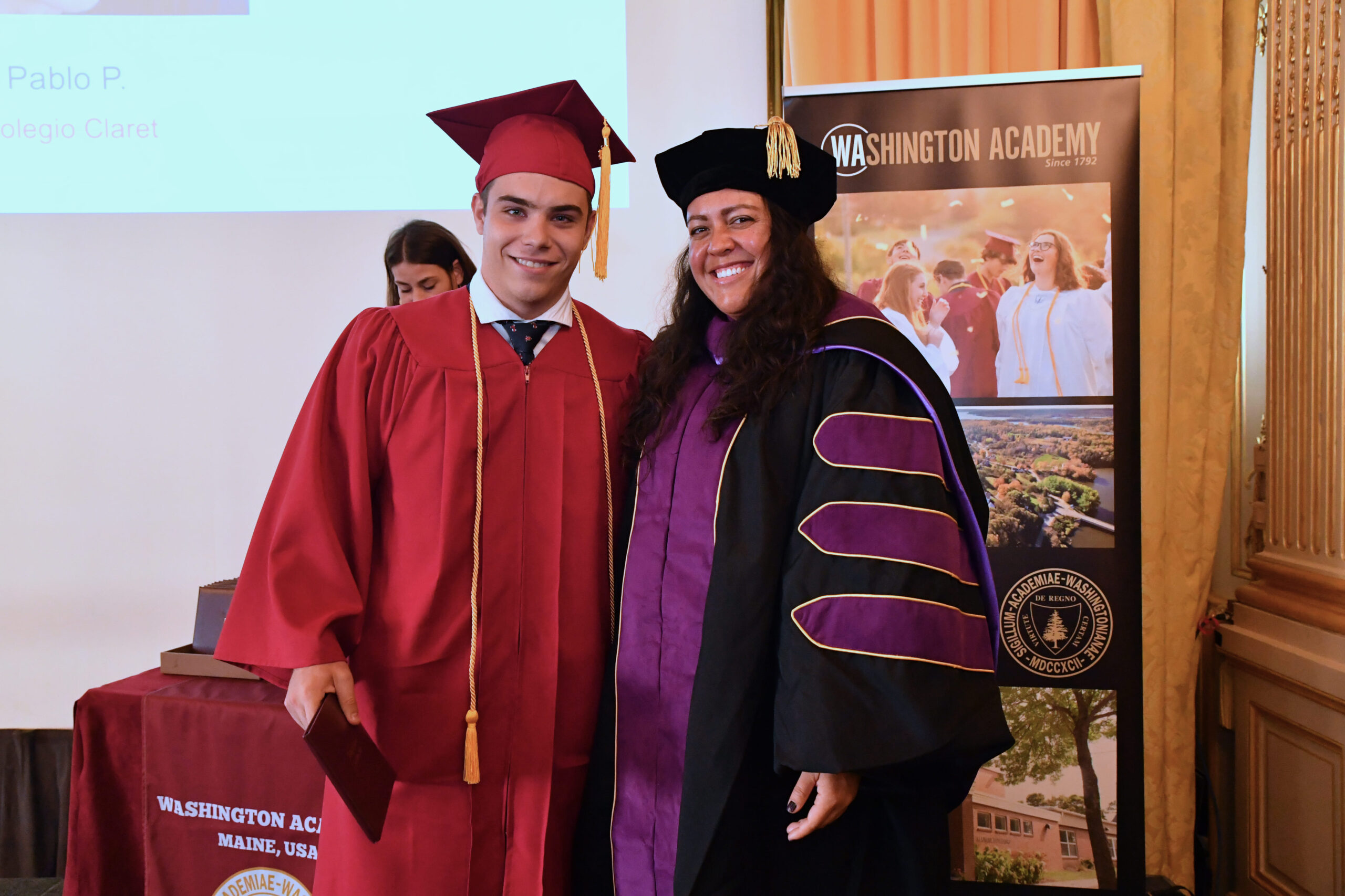 El alumno posa para una foto con la directora de su programa al recibir su diploma americano en la ceremonia de la graduación.